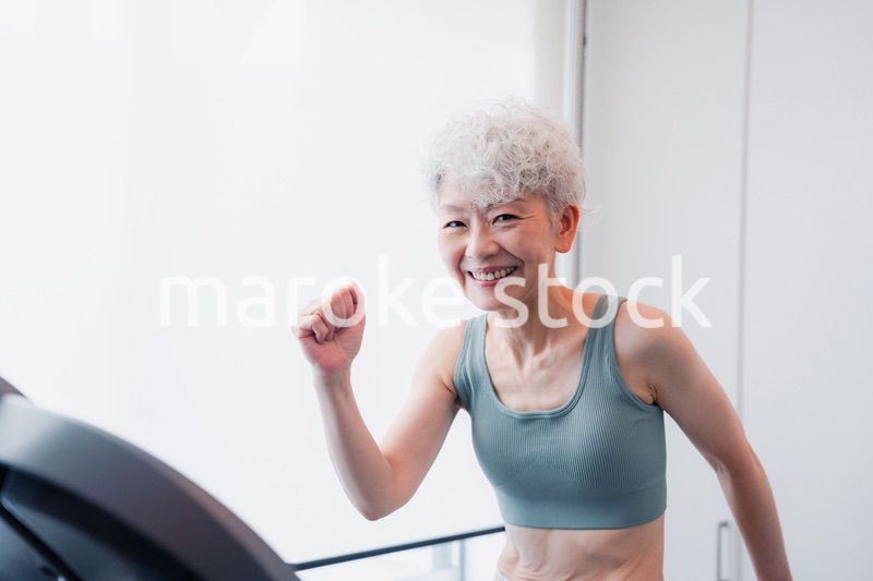ジムでランニングマシンに乗るシニアの女性