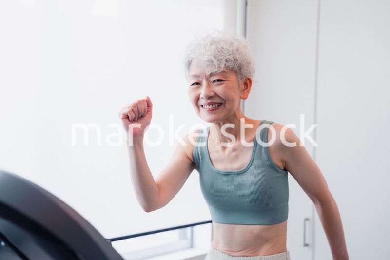 ジムでランニングマシンに乗るシニアの女性