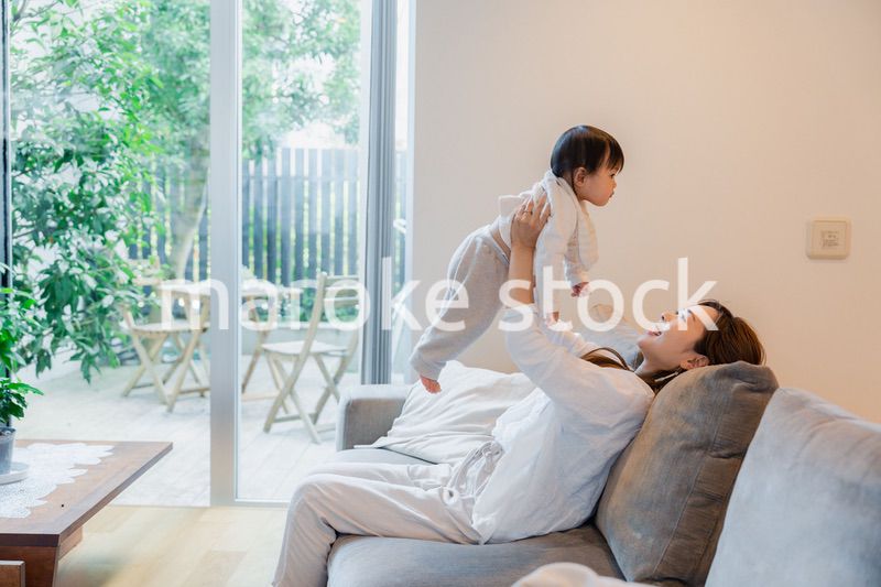 おうちで赤ちゃんに高い高いをするお母さん