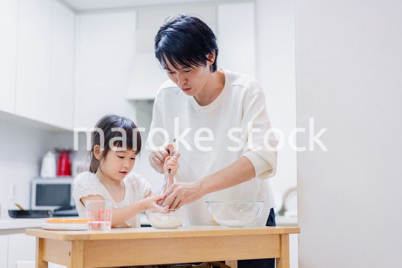 パパと一緒にクッキングをする小さな女の子