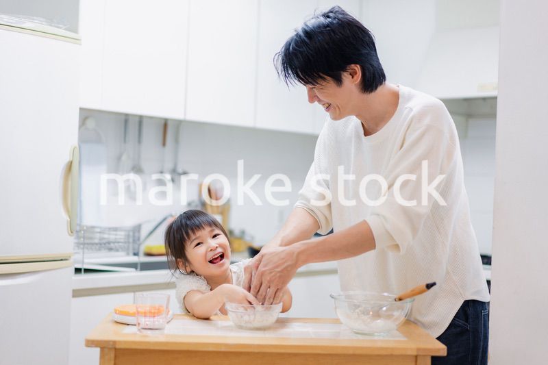 パパと一緒にクッキングをする小さな女の子