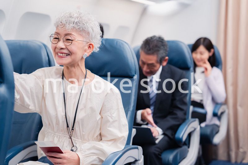 機内エンターテイメントを楽しむ高齢の女性