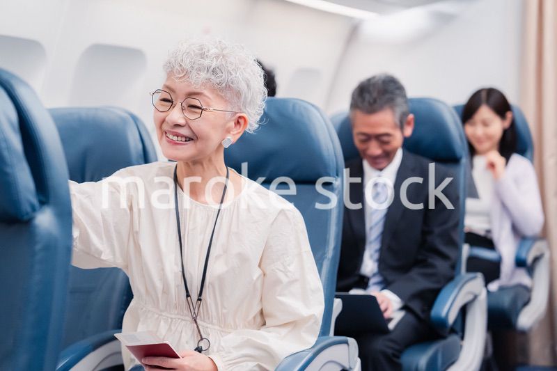 機内エンターテイメントを楽しむ高齢の女性