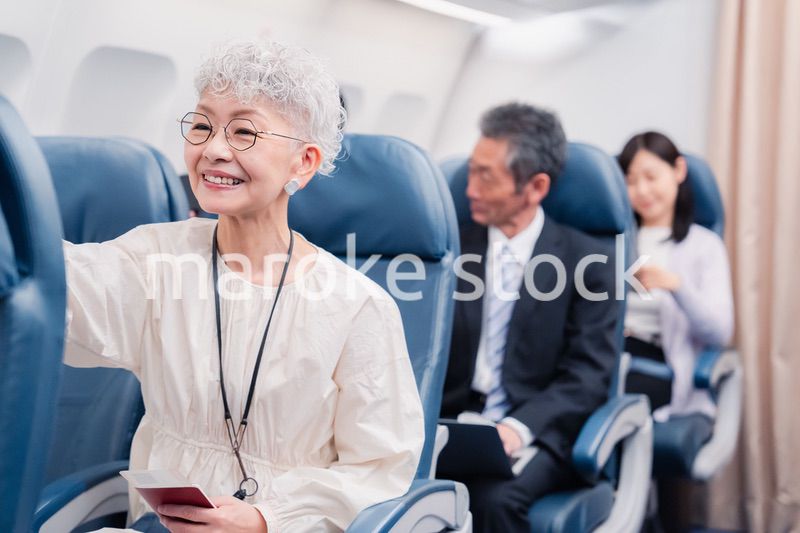 機内エンターテイメントを楽しむ高齢の女性