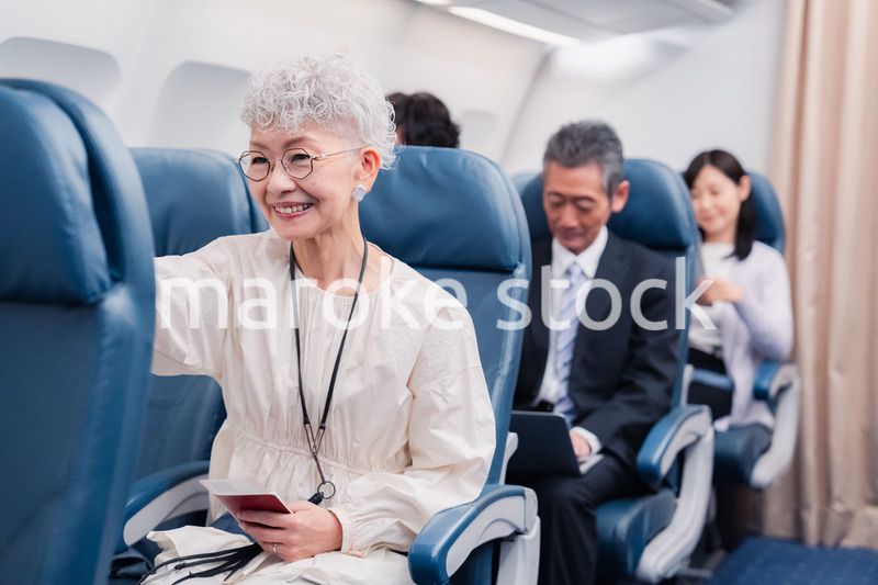 機内エンターテイメントを楽しむ高齢の女性