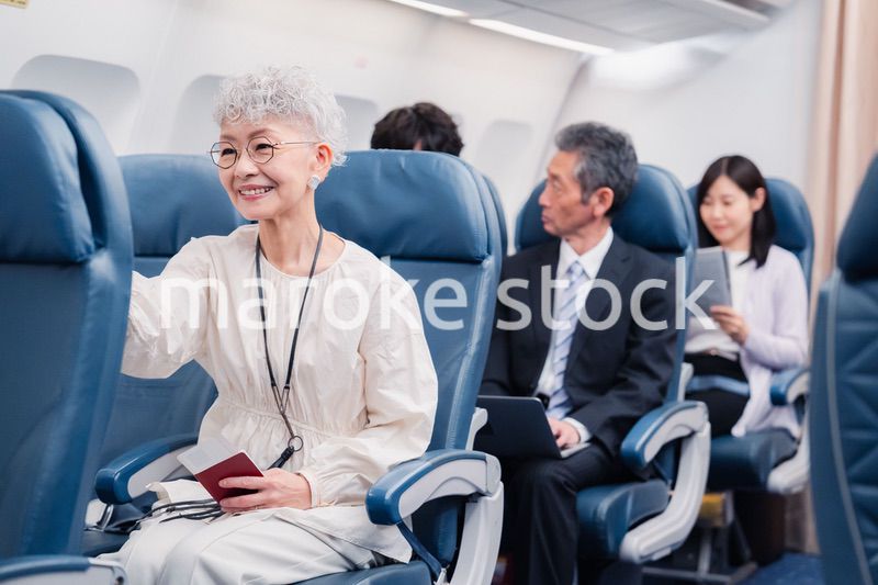 機内エンターテイメントを楽しむ高齢の女性