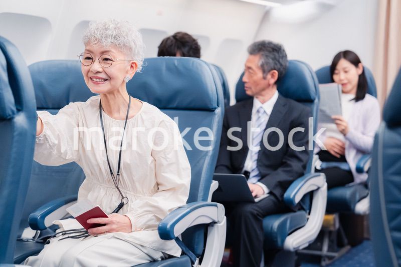 機内エンターテイメントを楽しむ高齢の女性