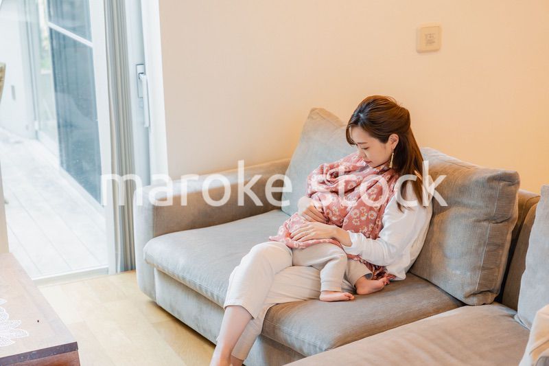 ソファーで赤ちゃんに授乳をするお母さん