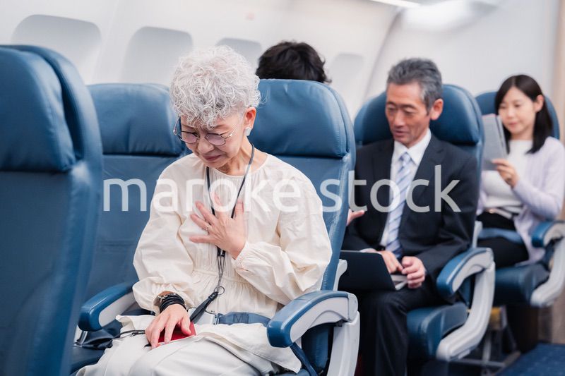 飛行機の機内で体調不良に苦しむ高齢の女性