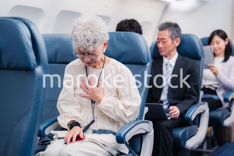 飛行機の機内で体調不良に苦しむ高齢の女性