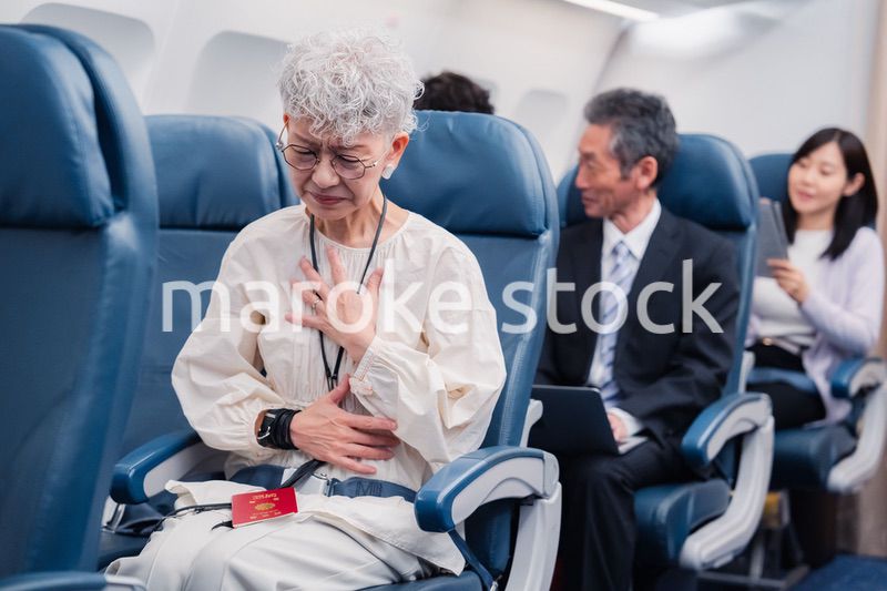 飛行機の機内で体調不良に苦しむ高齢の女性