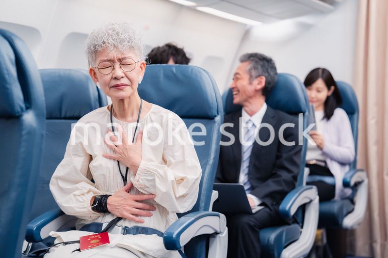 飛行機の機内で体調不良に苦しむ高齢の女性