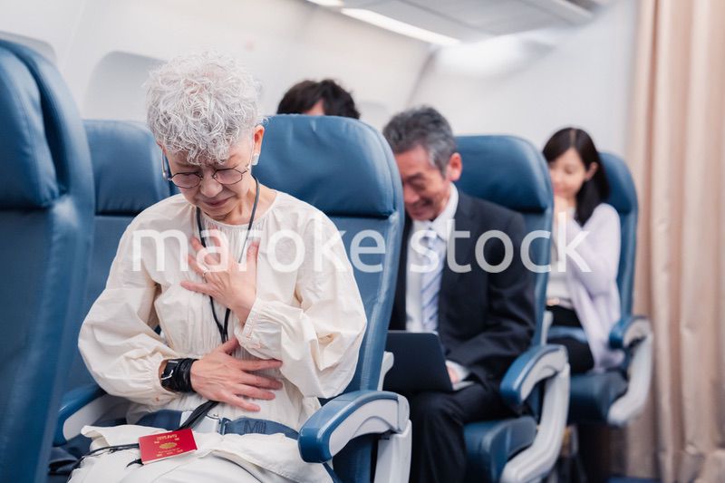 飛行機の機内で体調不良に苦しむ高齢の女性