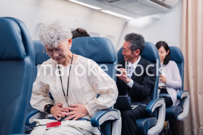 飛行機の機内で体調不良に苦しむ高齢の女性