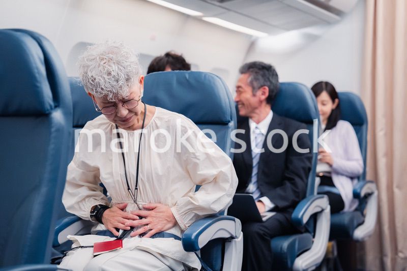 飛行機の機内で体調不良に苦しむ高齢の女性
