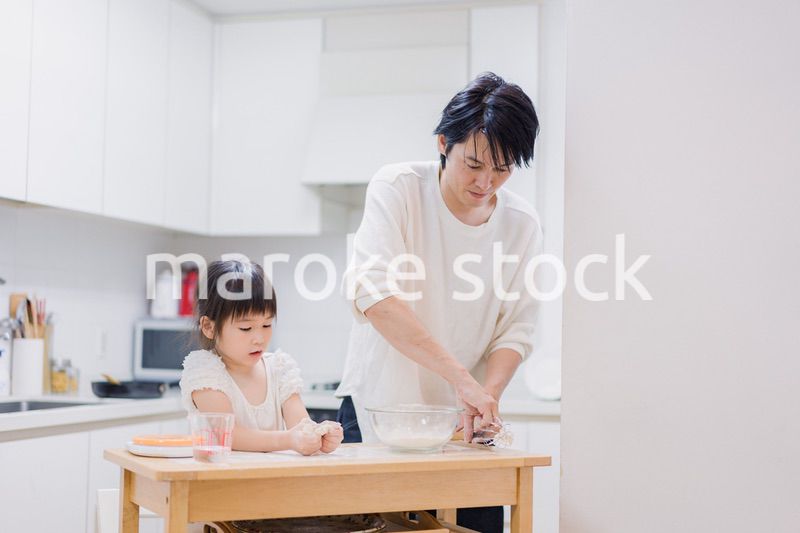 パパと一緒にクッキングをする小さな女の子