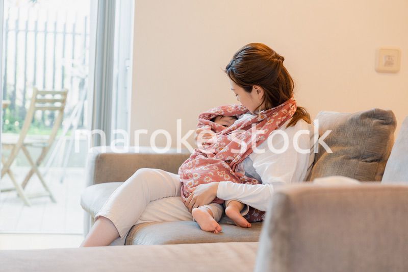 ソファーで赤ちゃんに授乳をするお母さん