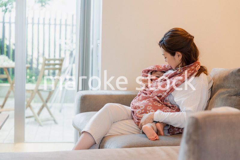 ソファーで赤ちゃんに授乳をするお母さん