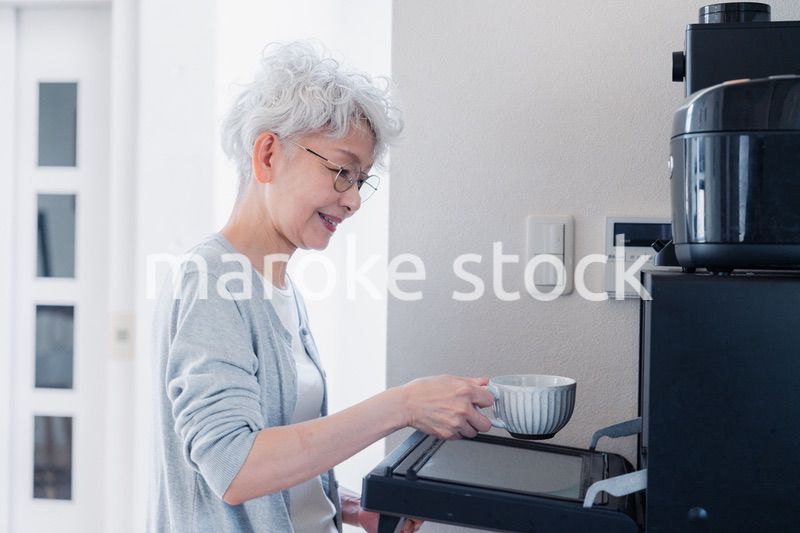 電子レンジでカップを温めるシニアの女性