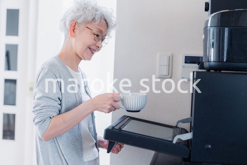 電子レンジでカップを温めるシニアの女性