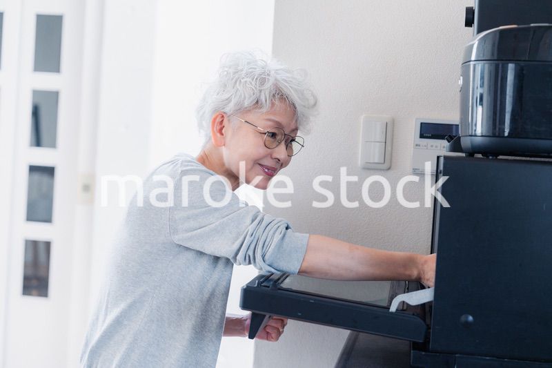 電子レンジでカップを温めるシニアの女性