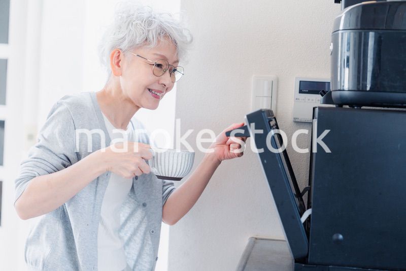 電子レンジでカップを温めるシニアの女性