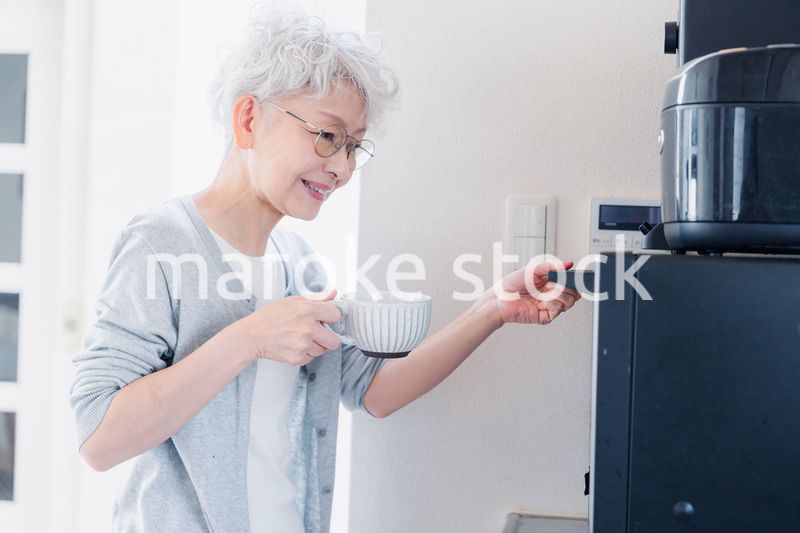 電子レンジでカップを温めるシニアの女性