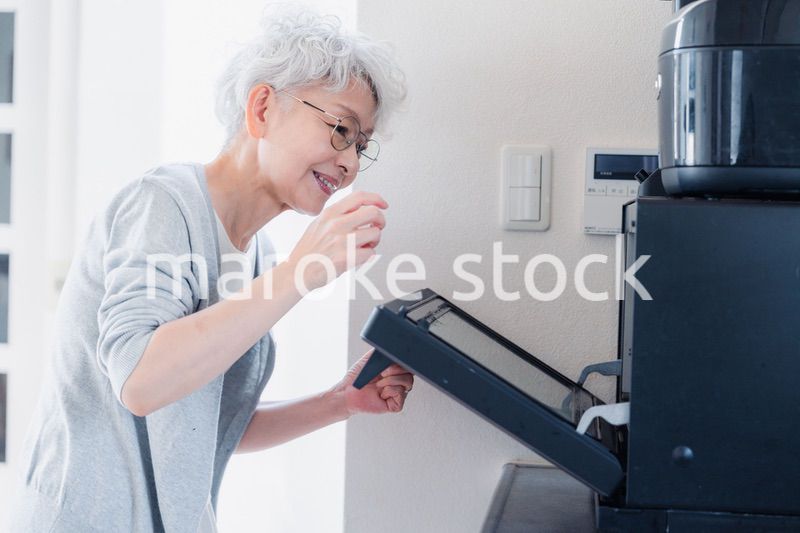 電子レンジでカップを温めるシニアの女性