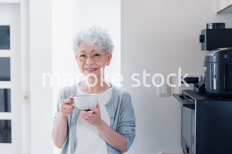 電子レンジでカップを温めるシニアの女性