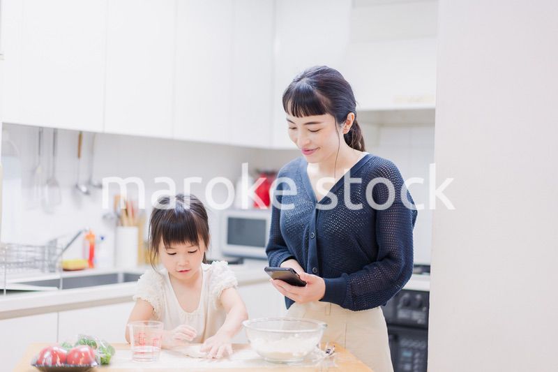 ママとスマホでレシピを見ながら料理をする娘