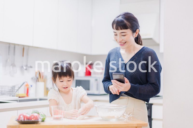 ママとスマホでレシピを見ながら料理をする娘
