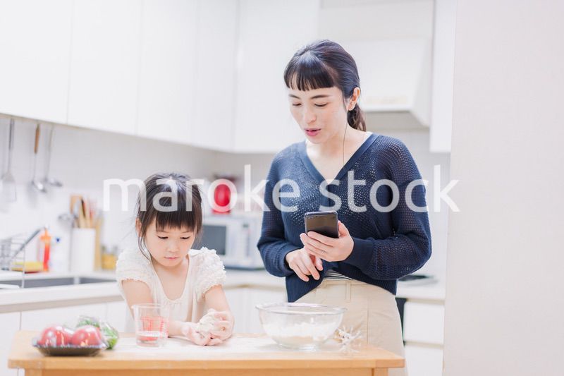 ママとスマホでレシピを見ながら料理をする娘