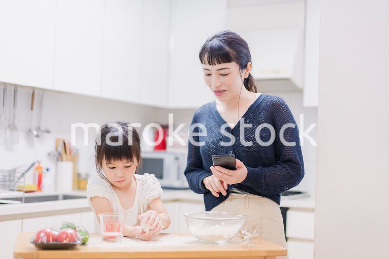 ママとスマホでレシピを見ながら料理をする娘