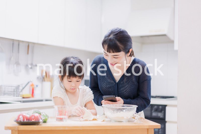 ママとスマホでレシピを見ながら料理をする娘