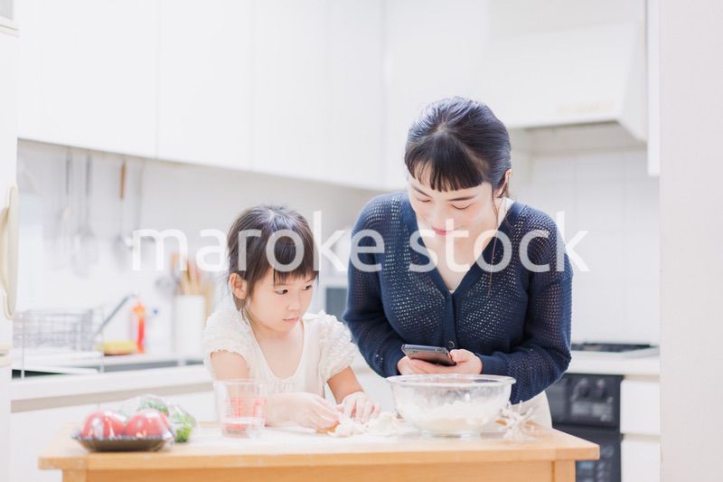ママとスマホでレシピを見ながら料理をする娘