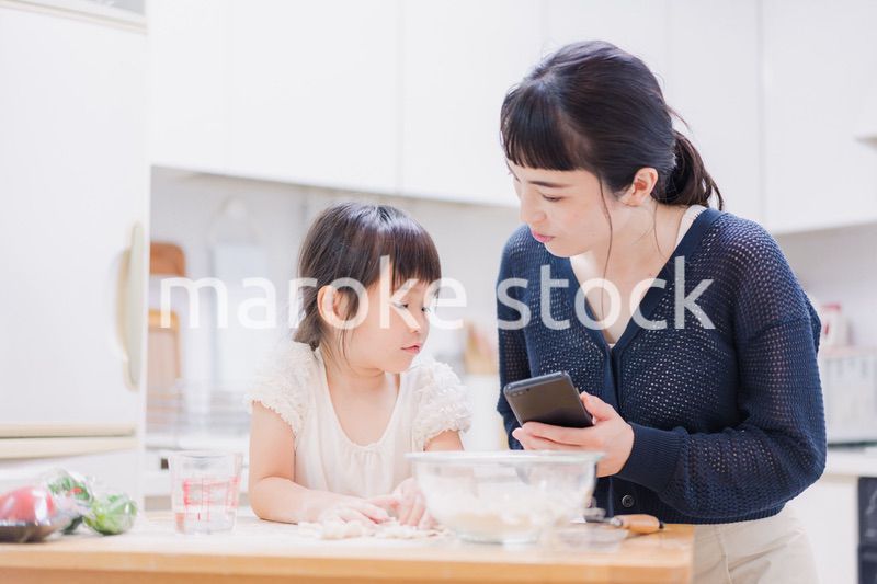 ママとスマホでレシピを見ながら料理をする娘