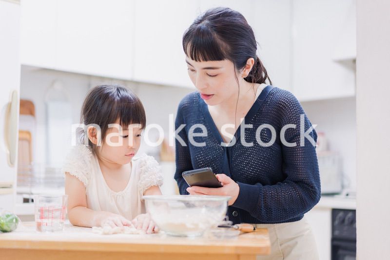 ママとスマホでレシピを見ながら料理をする娘