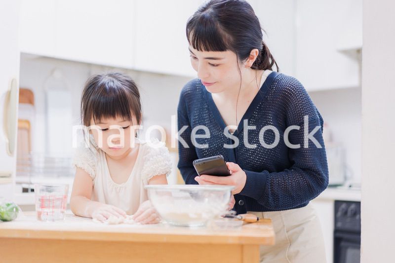 ママとスマホでレシピを見ながら料理をする娘