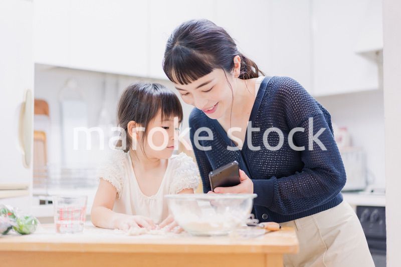 ママとスマホでレシピを見ながら料理をする娘