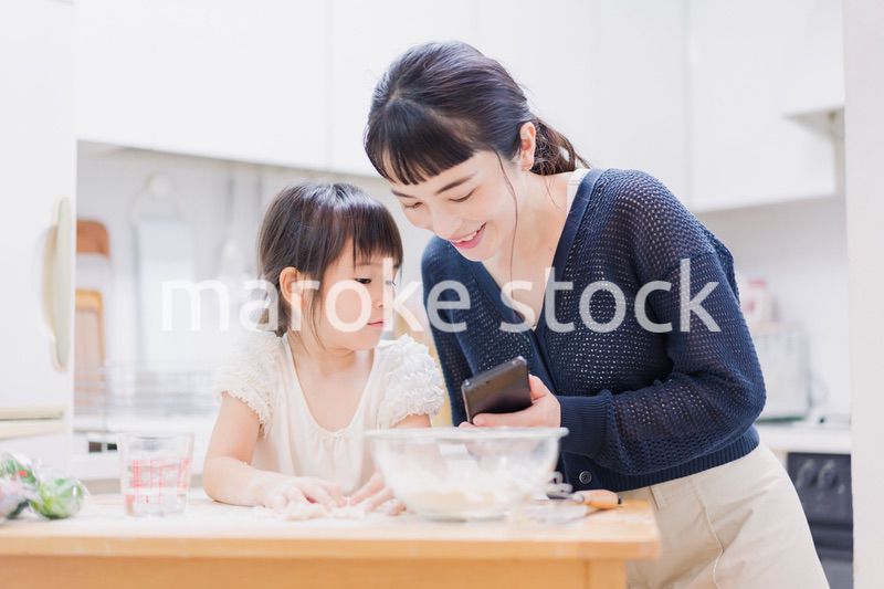 ママとスマホでレシピを見ながら料理をする娘