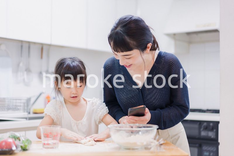 ママとスマホでレシピを見ながら料理をする娘