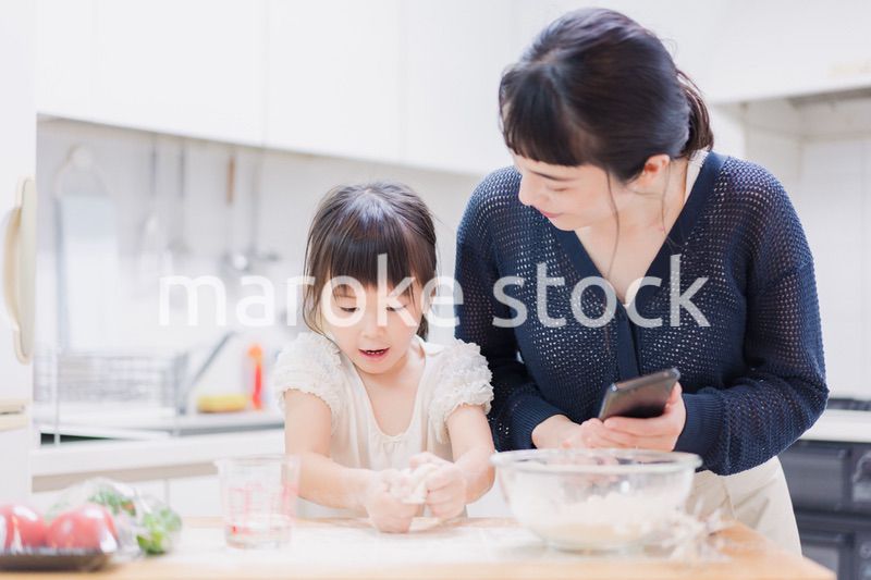 ママとスマホでレシピを見ながら料理をする娘