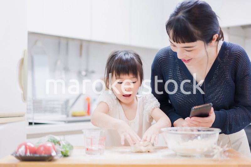 ママとスマホでレシピを見ながら料理をする娘