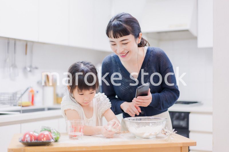 ママとスマホでレシピを見ながら料理をする娘