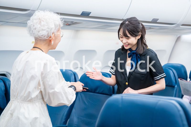高齢の乗客を案内するキャビンアテンダント