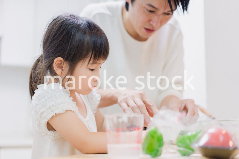 パパと一緒にクッキングをする小さな女の子