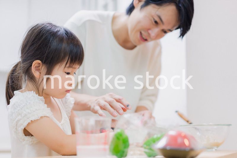 パパと一緒にクッキングをする小さな女の子