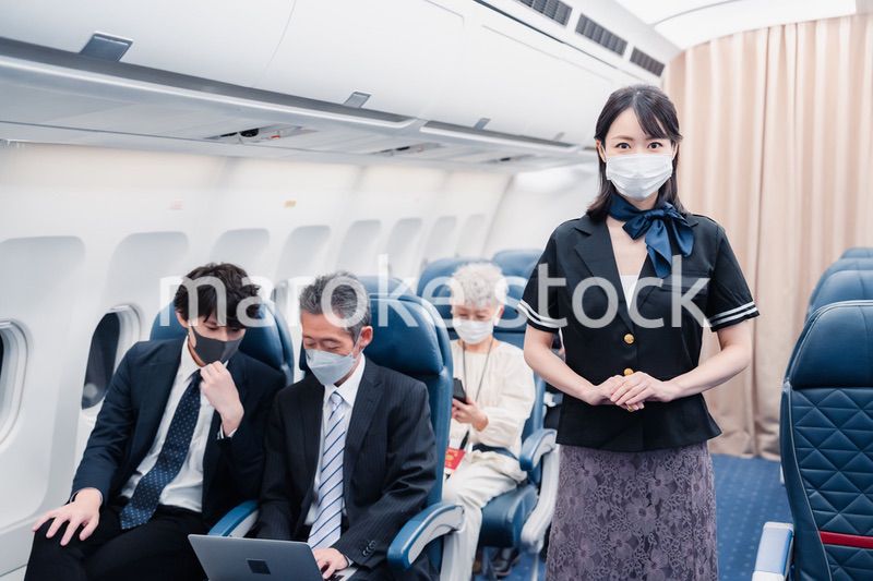 マスクをしてお客様の案内をするキャビンアテンダント
