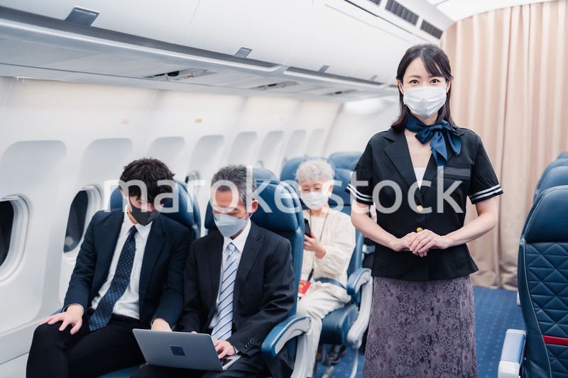 マスクをしてお客様の案内をするキャビンアテンダント