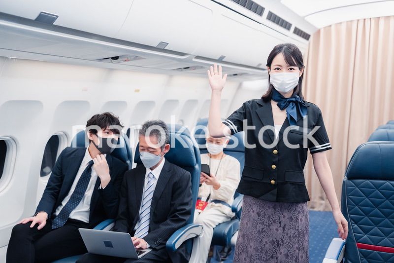 マスクをしてお客様の案内をするキャビンアテンダント